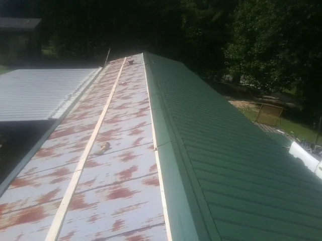 Old rusted panels beside newly installed green metal roofing — Wind Damage Roof Repair by Roofing Brothers in Emmitsburg