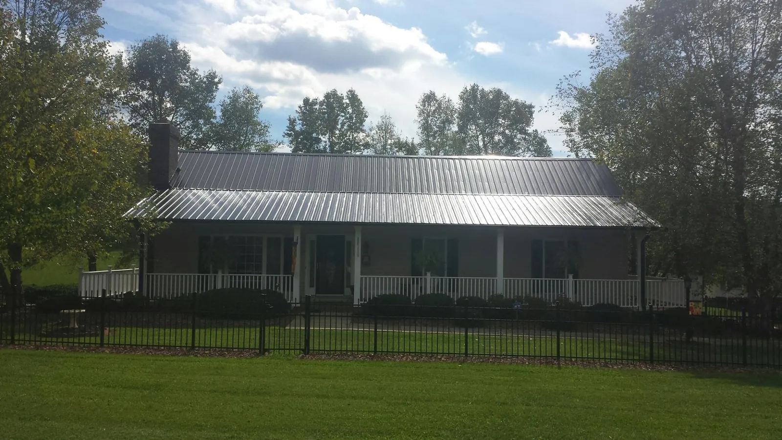 Gray metal roof on a brick ranch with a full width front porch — Gutter Guard Installation work by our crew in Emmitsburg