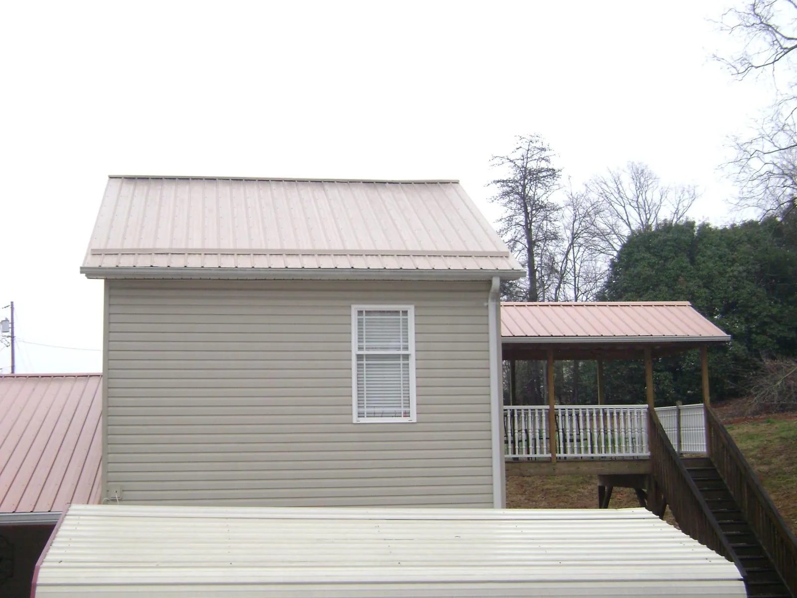 Tan metal roofs on a two story addition and attached porch, from a Roof Replacement job in Emmitsburg