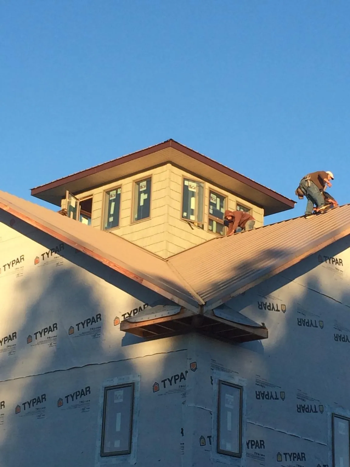 Roofers working around a rooftop cupola on a new metal roof at sunset — Roof Waterproofing in Emmitsburg by Roofing Brothers